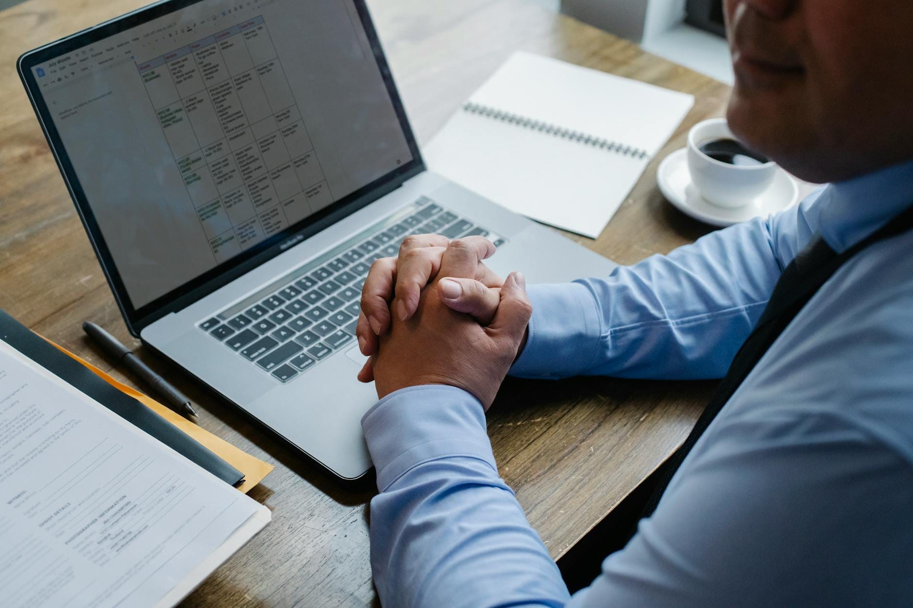 Mężczyzna przy biurku pracuje na laptopie z kubkiem kawy obok