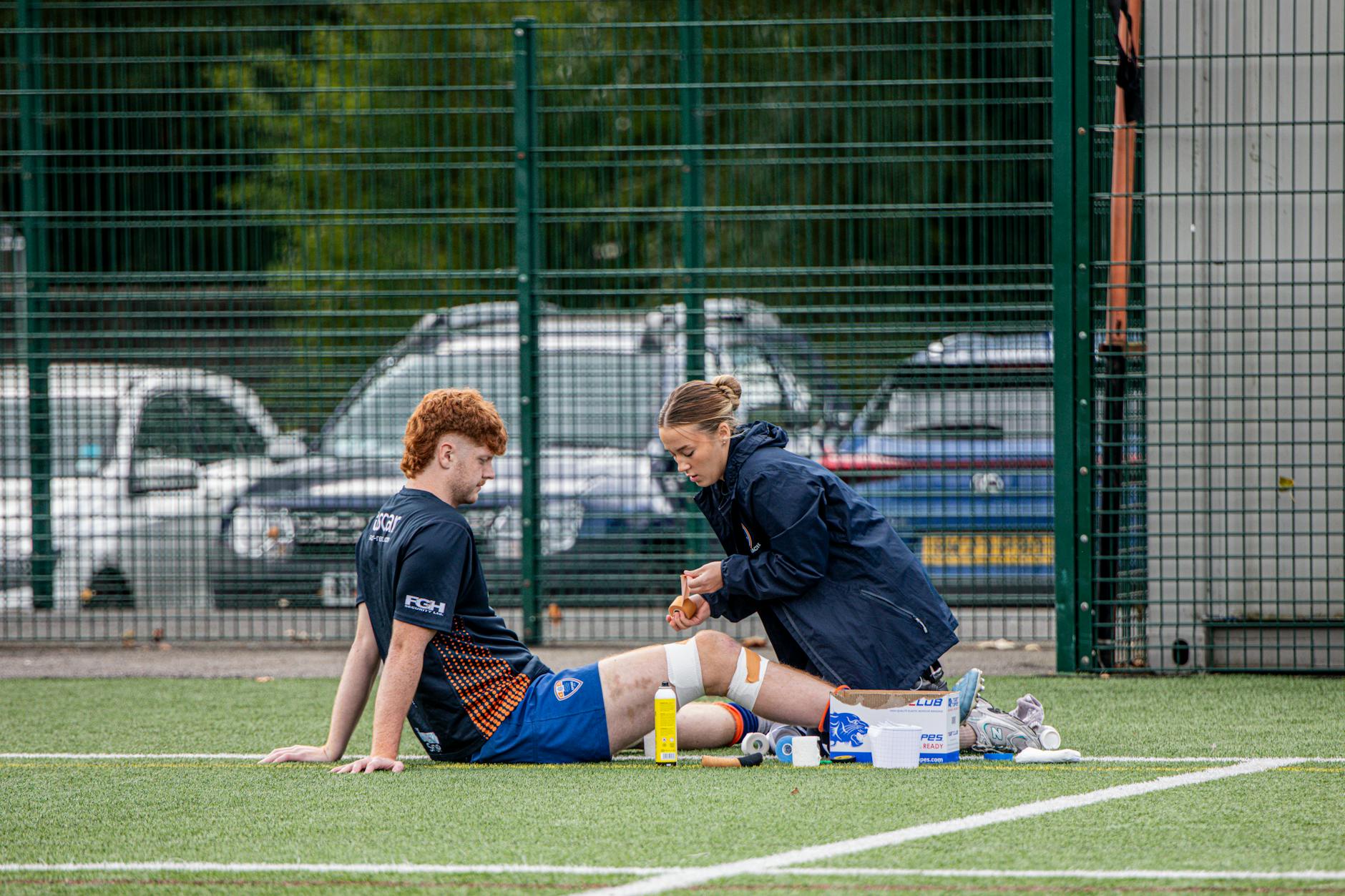 Terapeuta sportowy bada kontuzjowanego piłkarza na boisku