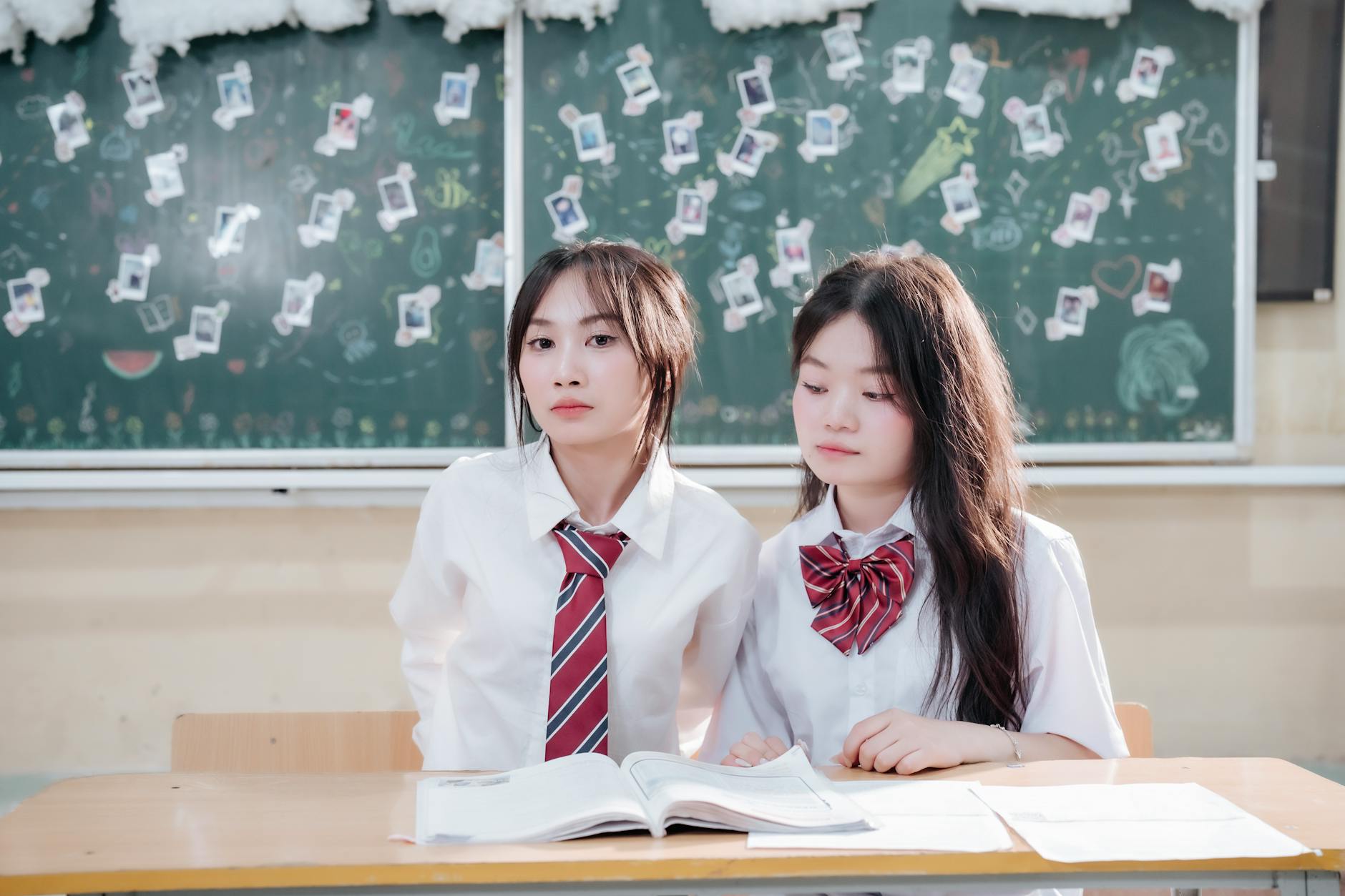 Dwójka uczniów w mundurkach przy biurku z książkami w klasie