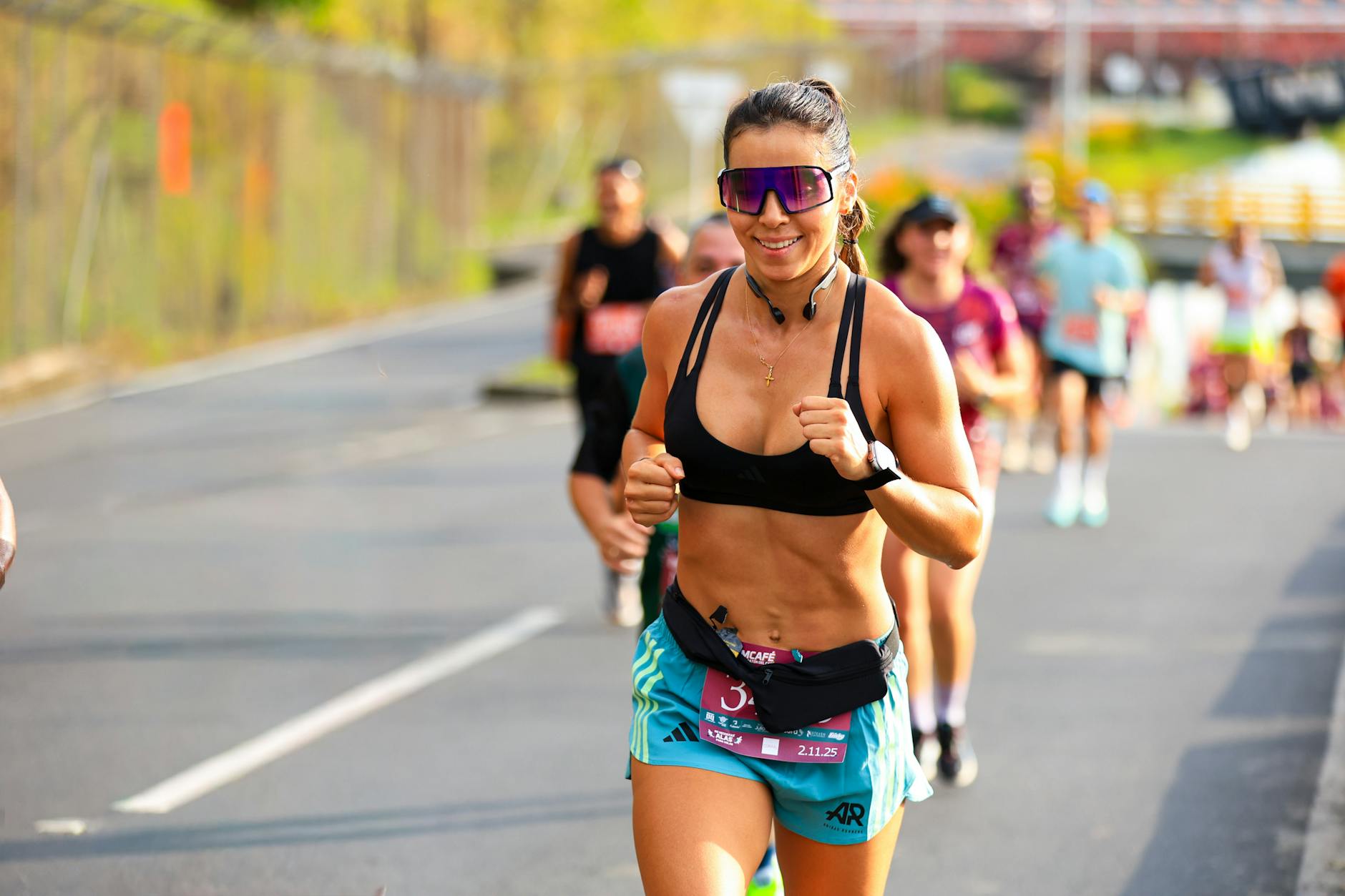 Biegaczka w maratonie biegnąca w słońcu, uśmiechnięta i skupiona