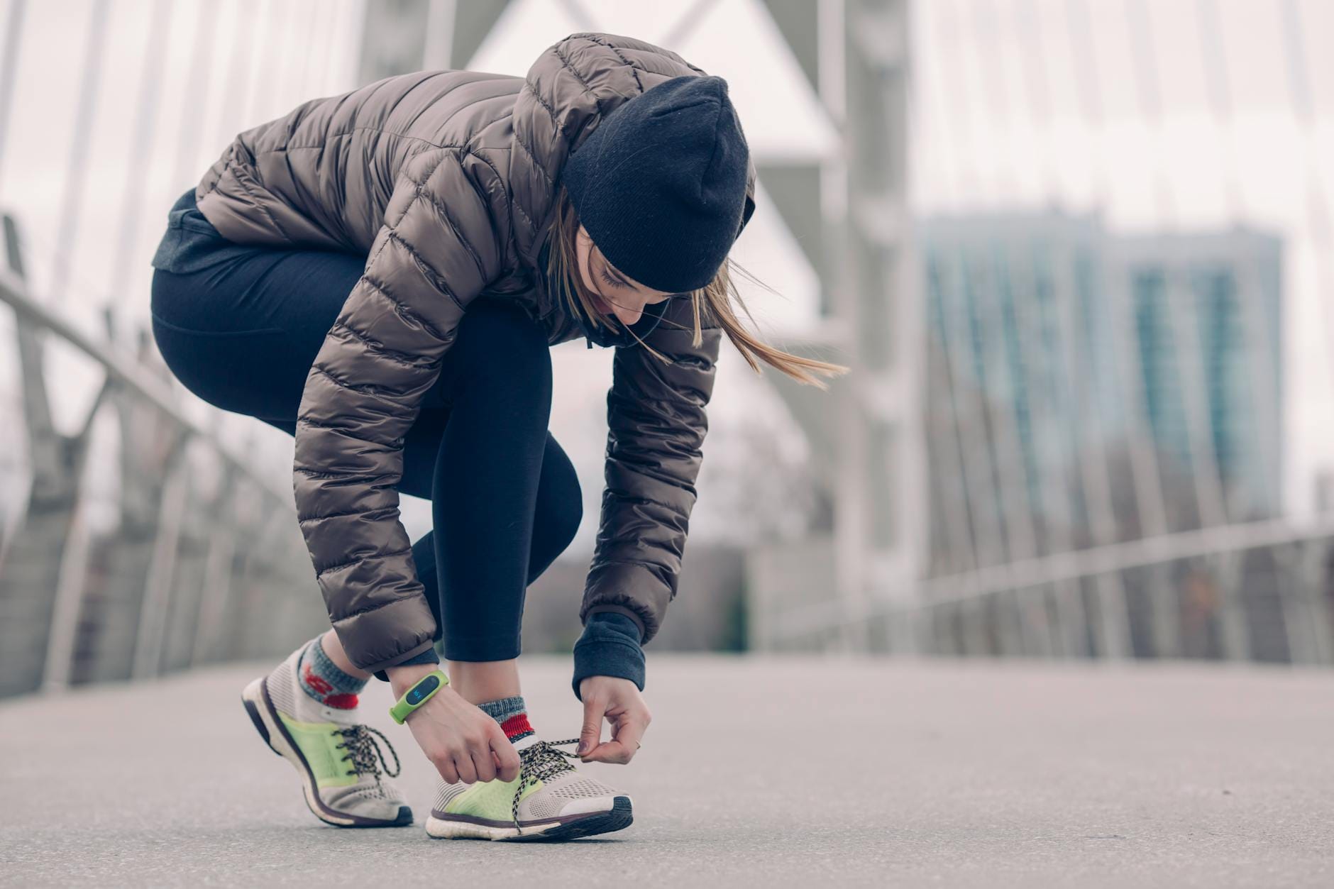 Kobieta w stroju sportowym wiąże buty do biegania na zimowym moście