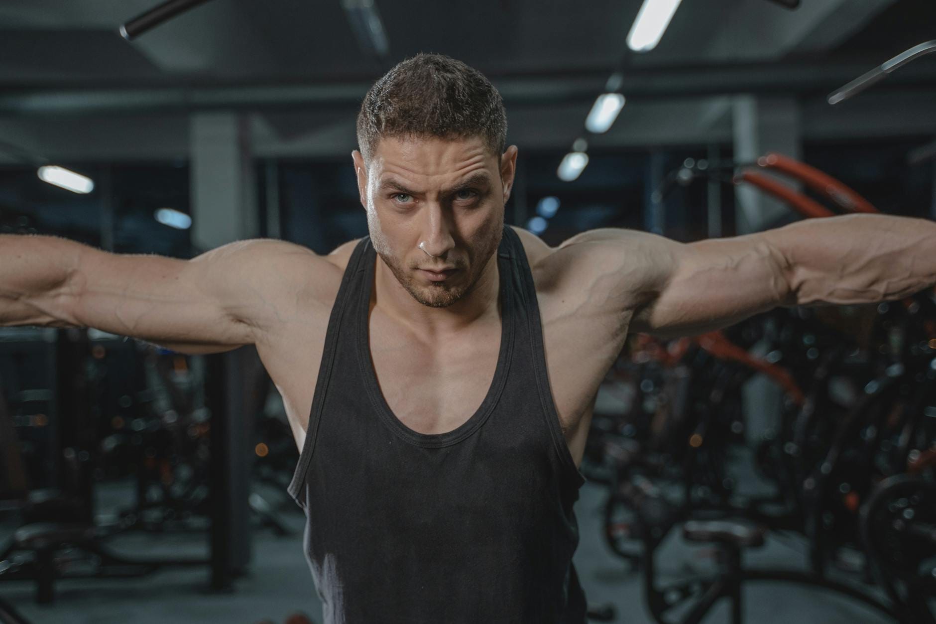 Skupiony mężczyzna w sportowym stroju ćwiczy barki na siłowni