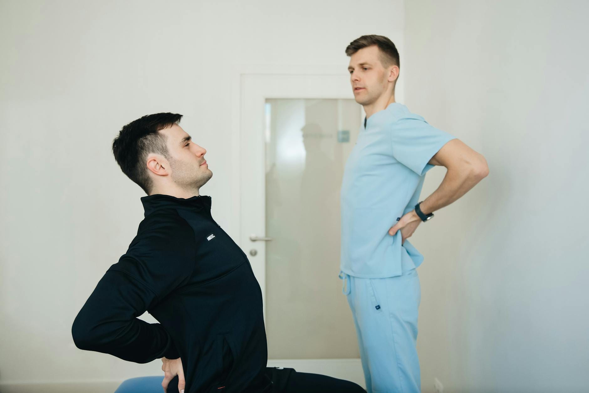 Fizjoterapeuta pokazuje pacjentowi ćwiczenia na plecy w gabinecie