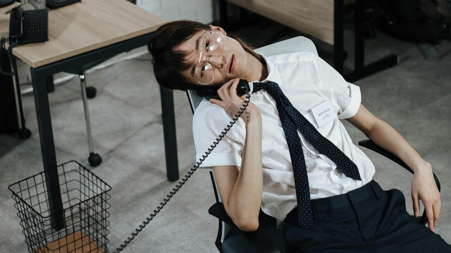 Mężczyzna w biurowym fotelu rozmawia przez telefon stacjonarny