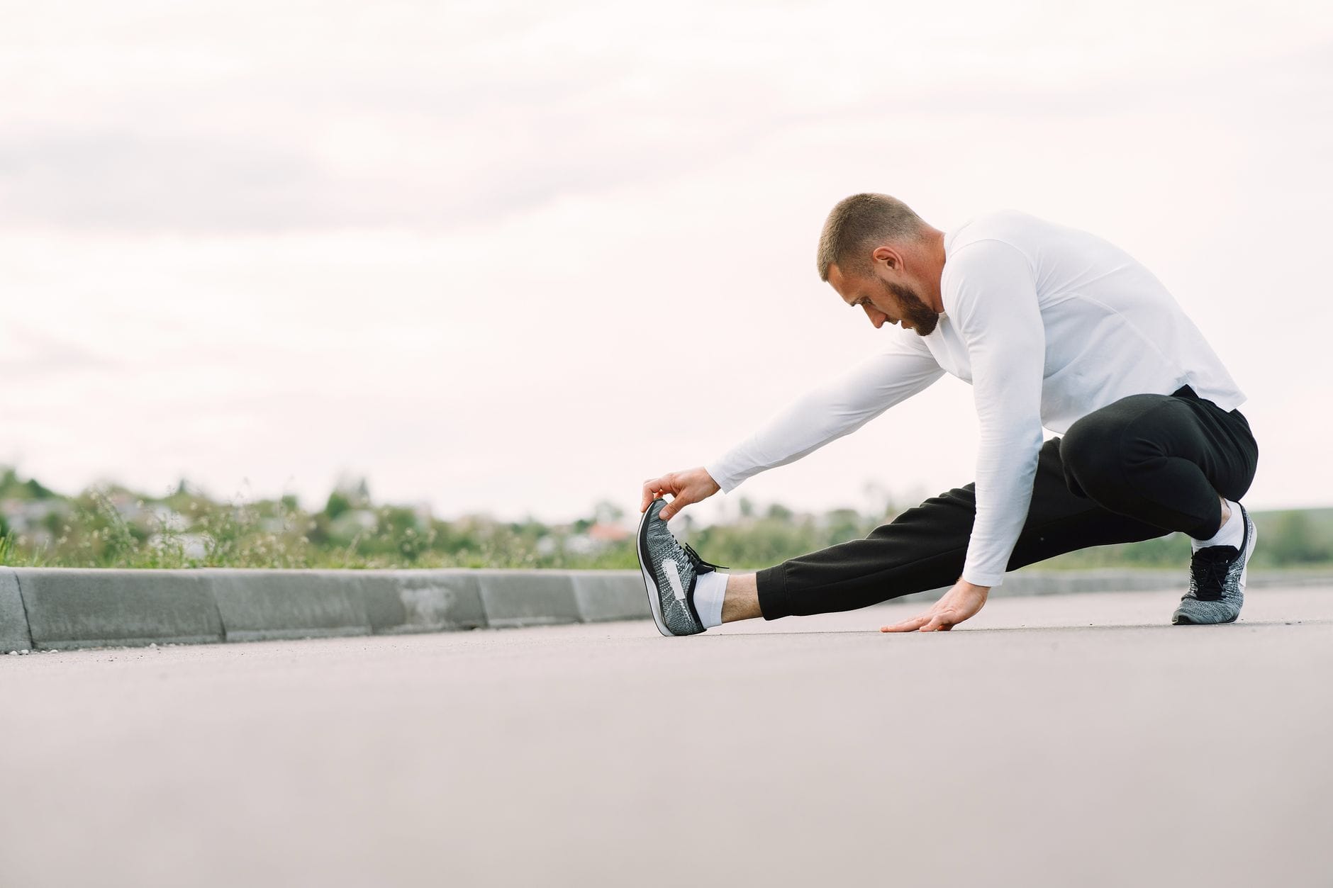 Biegacz w sportowym stroju rozciąga łydki na świeżym powietrzu