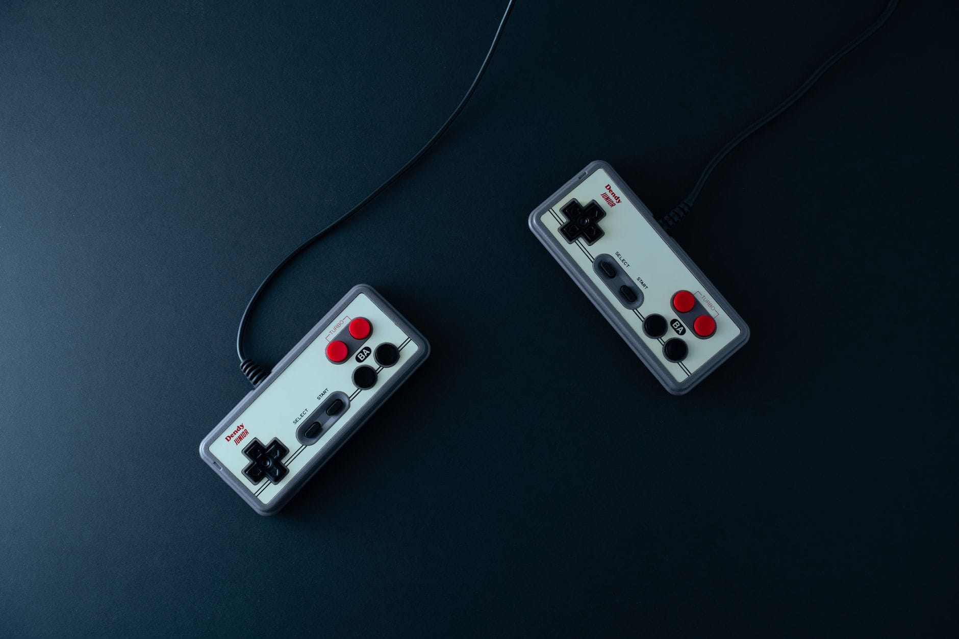 Dwa retro kontrolery do gier na ciemnym, minimalistycznym tle