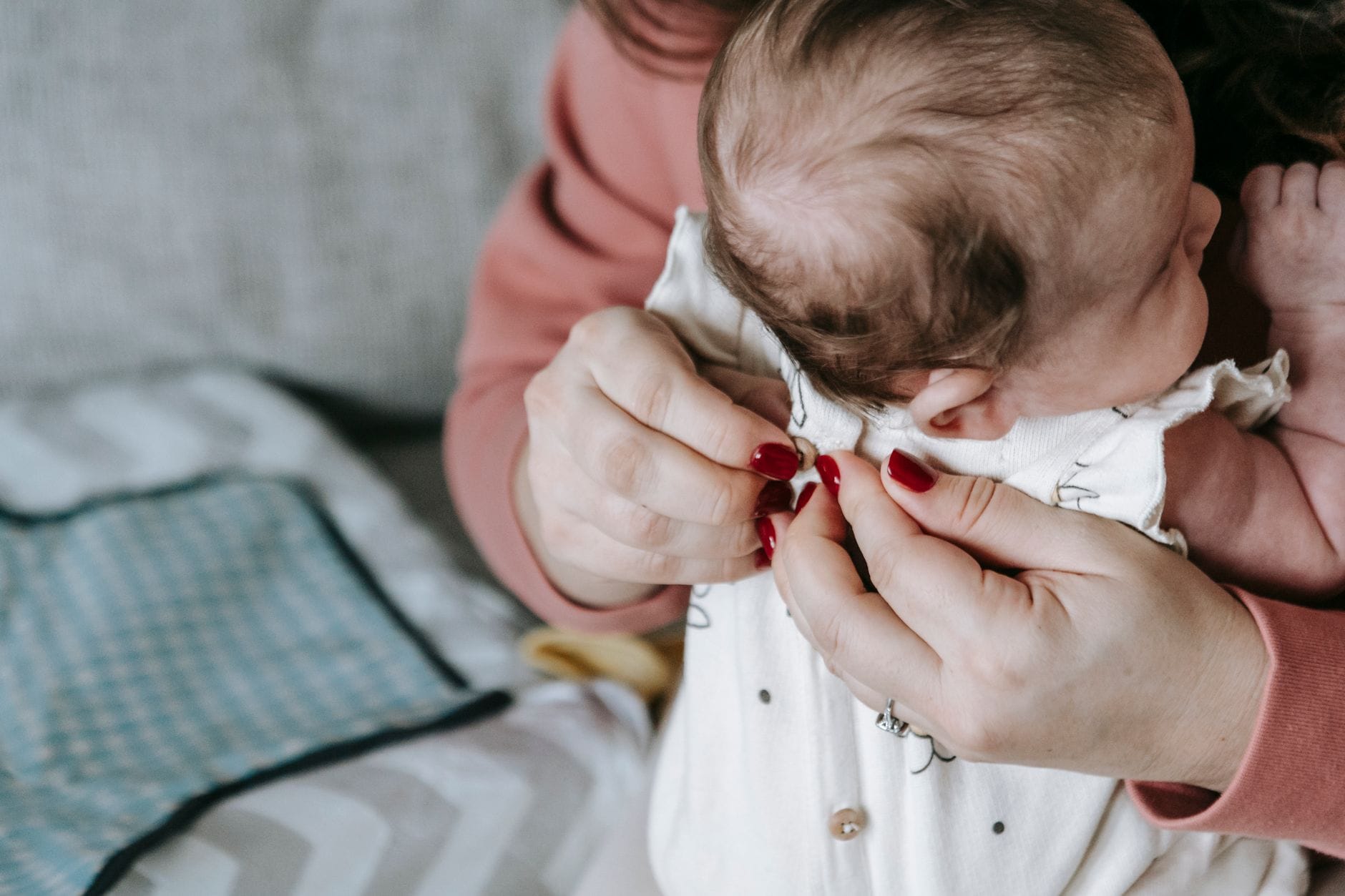 Mama delikatnie ubiera noworodka w domu, pielęgnując go z czułością